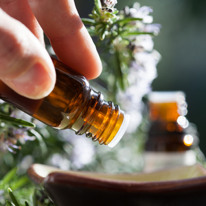 essential oil dropping out of bottle with green background