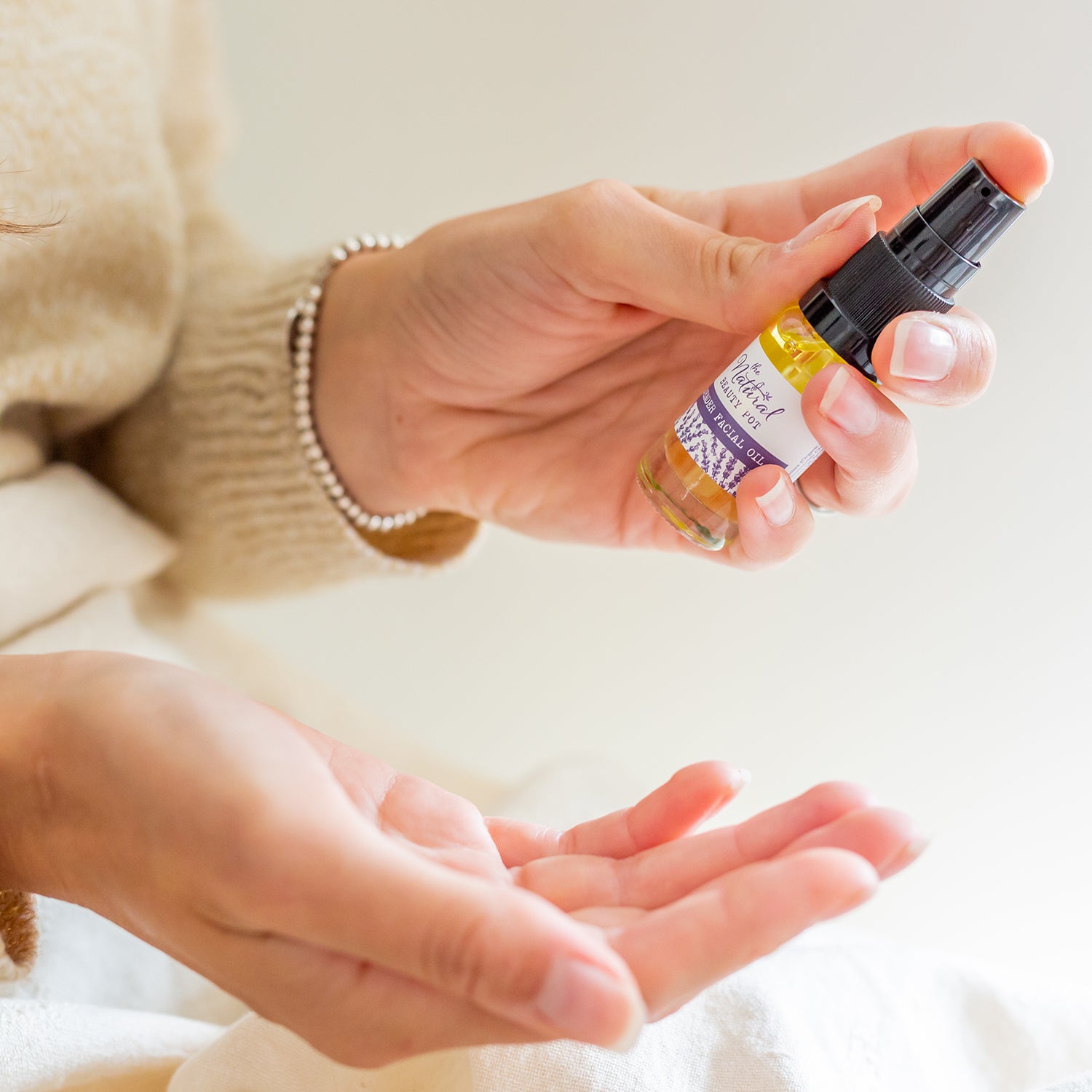 Person holding a small bottle of lavender facial oil for sensitive skin