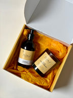 An yellow gift box containing products made by The Natural Beauty Pot products nestled in yellow tissue paper: a Lemongrass & Rosemary Hand Wash and Wild Lemongrass soy candle