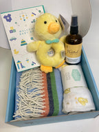 Baby Boy gift set with baby organic massage oil plush duck rattle, blue baby blanket, muslin, and other items in a box.
