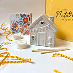 Ceramic house-shaped candle holder with candles and a decorative box The Natural Beauty Pot