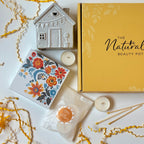 Gift Collection of candle tea lights, ceramic house holder, yellow tipped matches container, floral card, and yellow box on a white background.