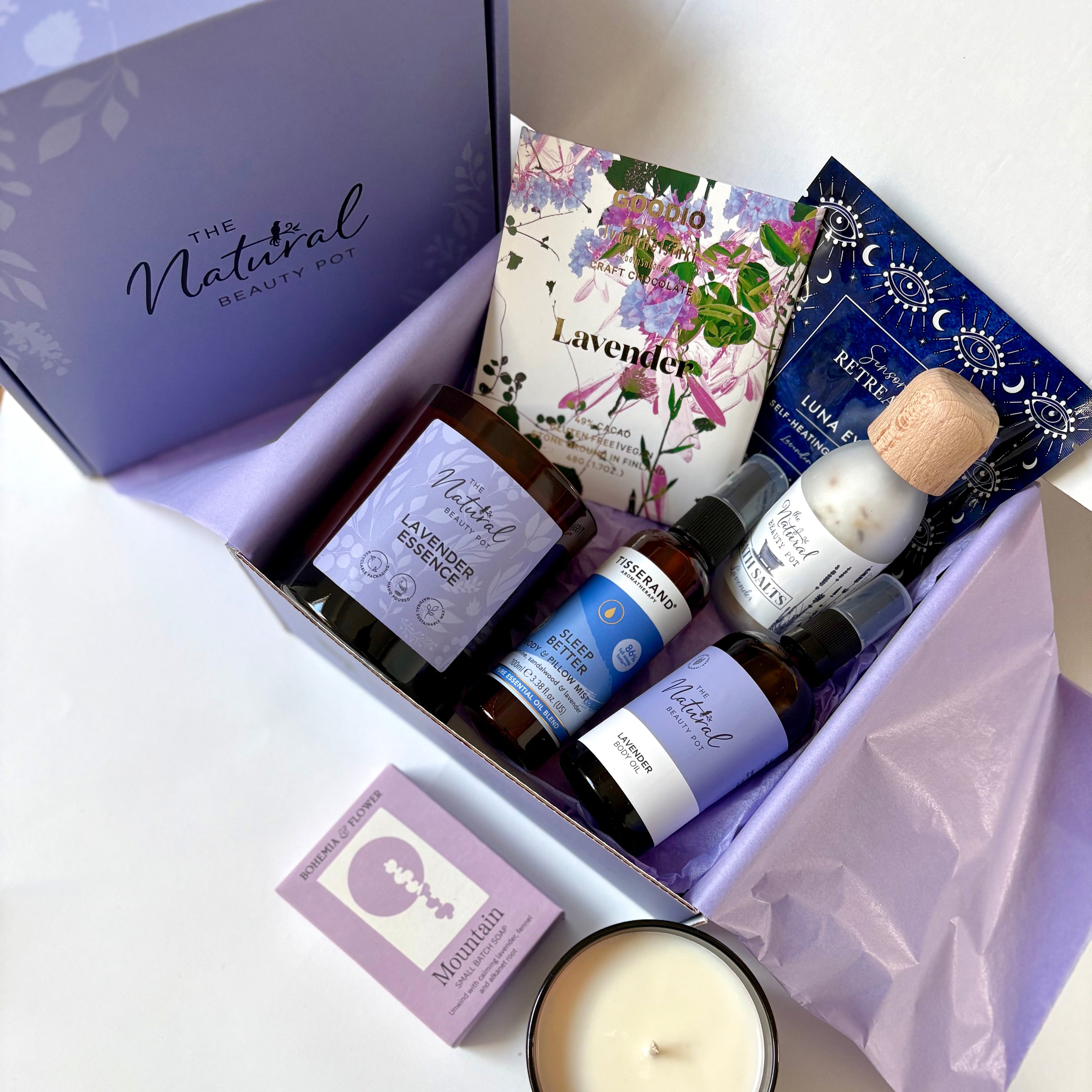 Set of natural products including candles, oils, and soaps in lavender a branded box.
