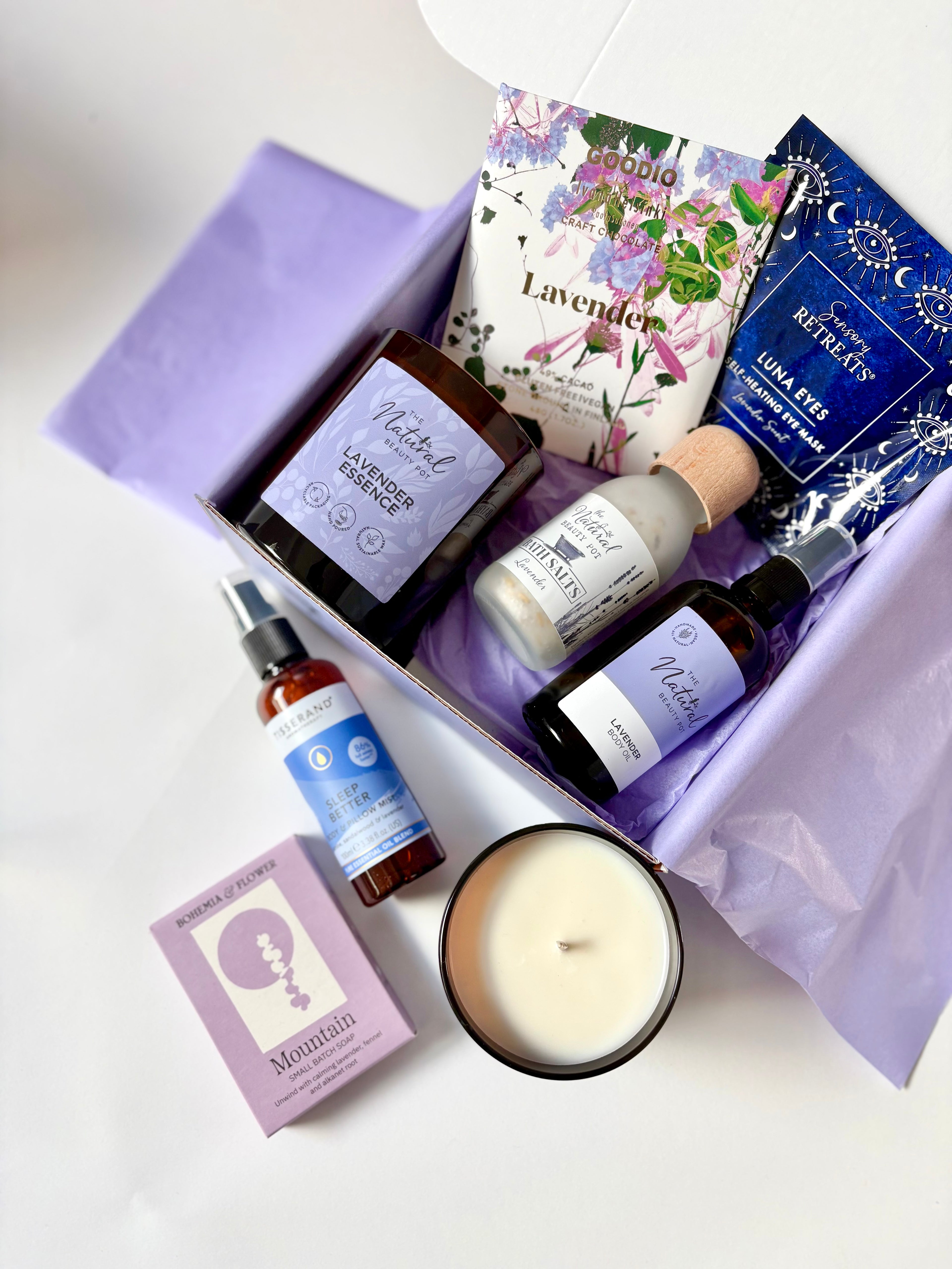 Lavender-themed gift set with candles, oils, bath salts, body mist, soap , eye mask and chocolate in a gift box.
