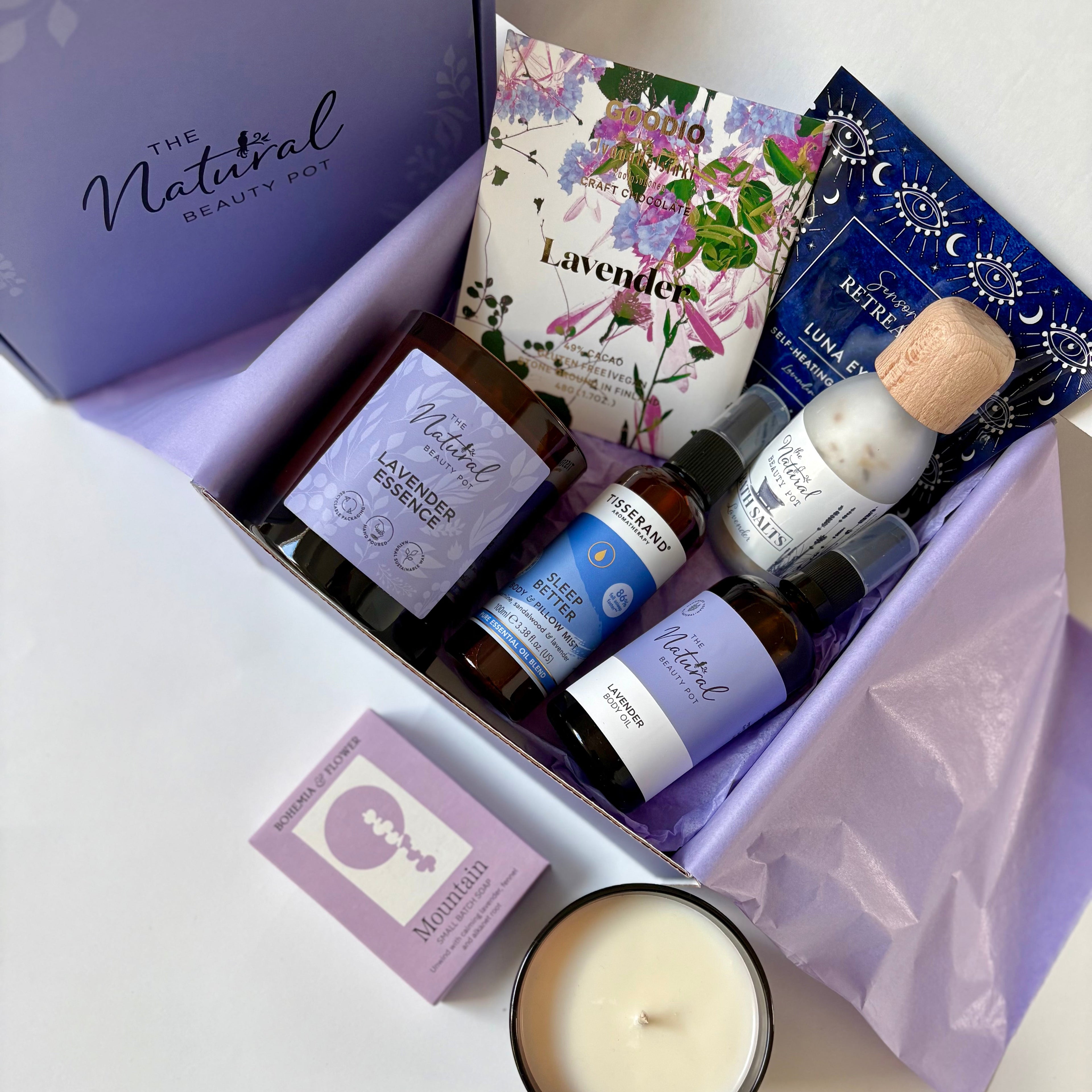Lavender-themed gift set with candles, oils, bath salts, body mist, soap , eye mask and chocolate in a gift box.
