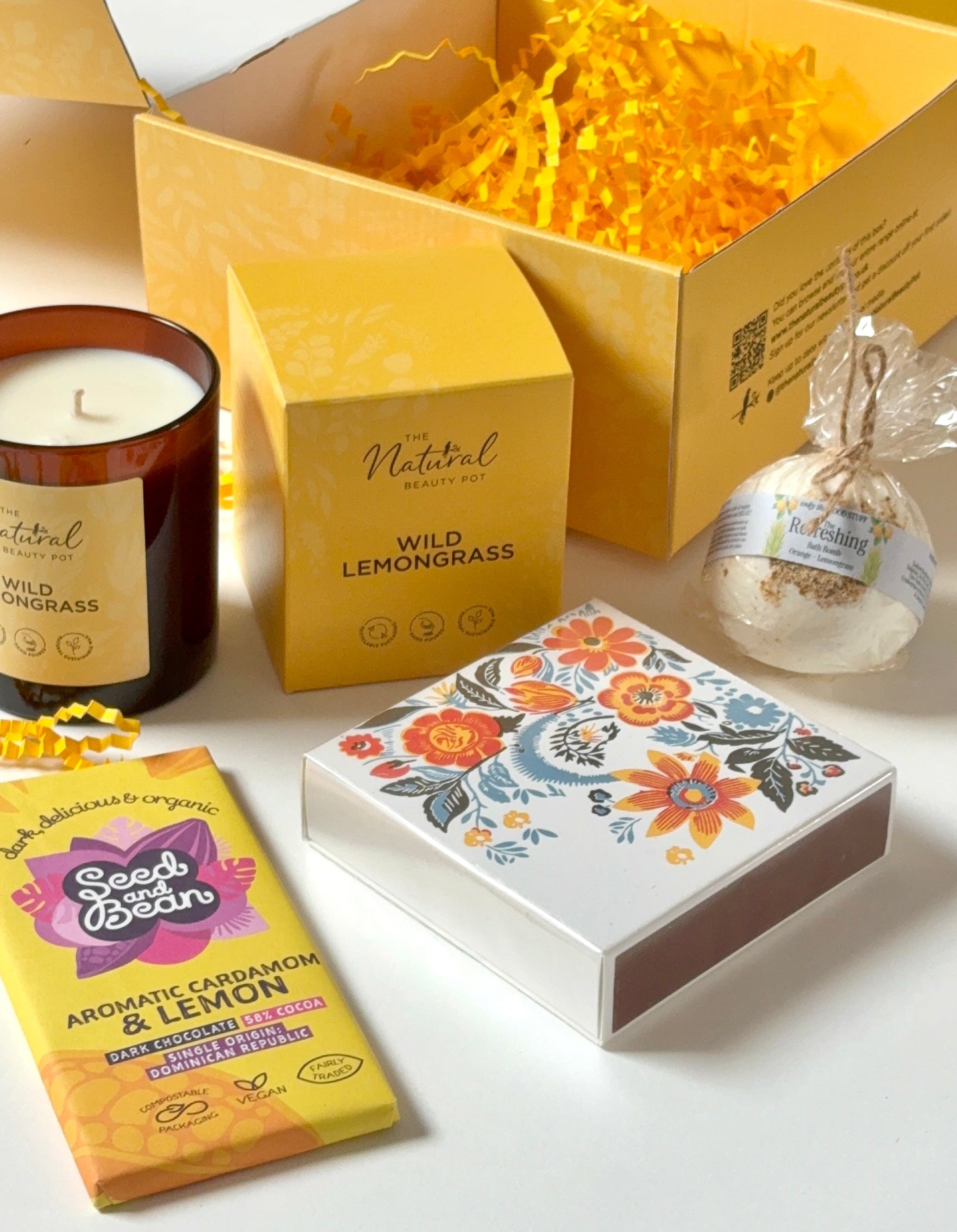 Gifting set with candle, bath bomb, matches and chocolate on a yellow gift box