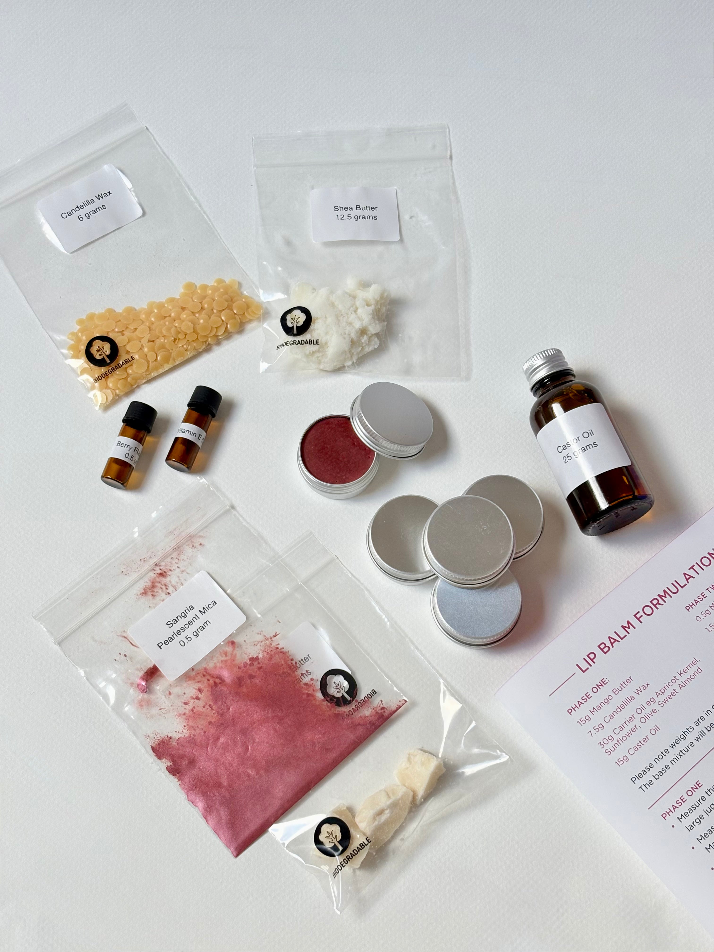 Lip balm making kit with ingredients and tins on a white surface