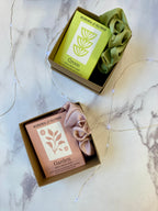 soap bar and scrunchie in decorative boxes on a marble surface