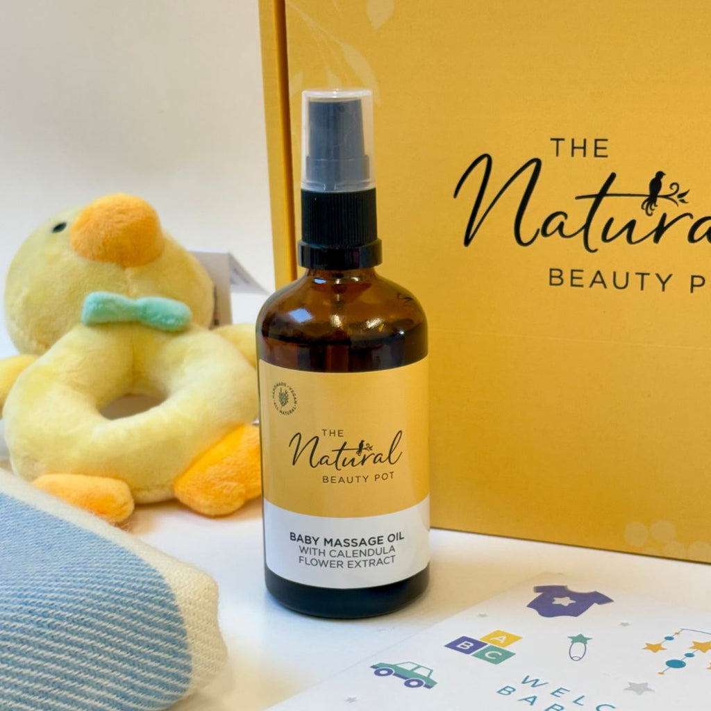 Baby massage oil bottle with 'The Natural Beauty Pot' branding, duck toy, and baby items in the background.