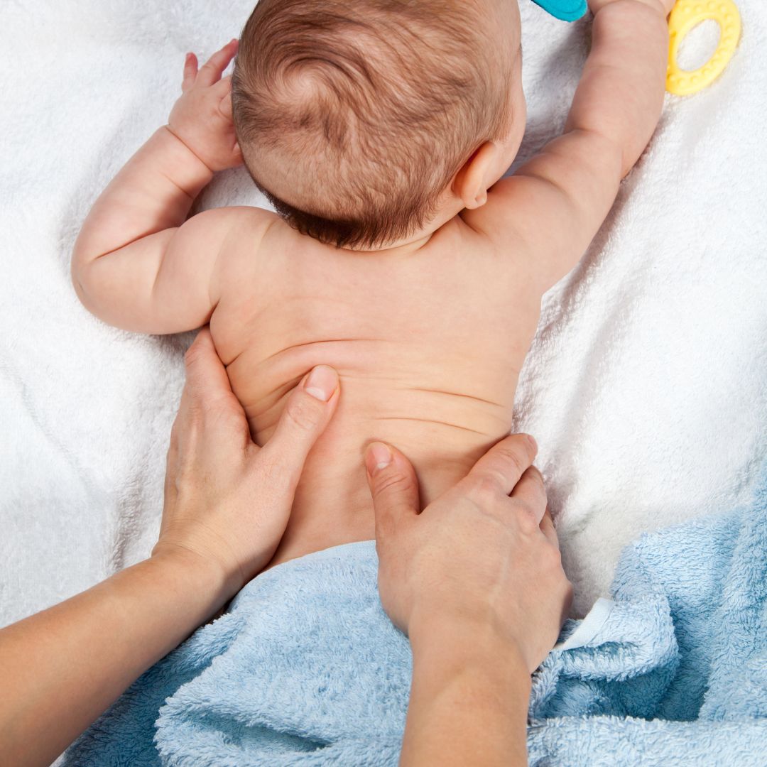 Baby being massaged on a white towel with blue towel underneath