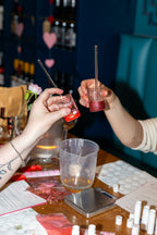 Two people clinking science beakers at a hen party making lip balms