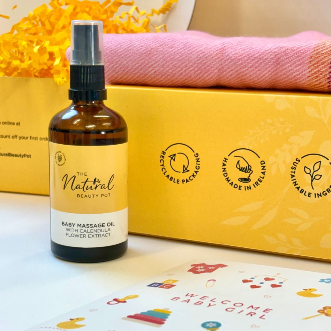 Baby massage oil bottle with a yellow box and pink towel in the background