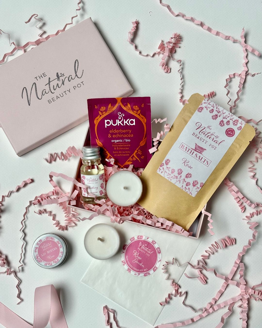pink wellbeing gift of natural beauty products including candles, cleansing oil, bath salts and lip balm in a pink box 